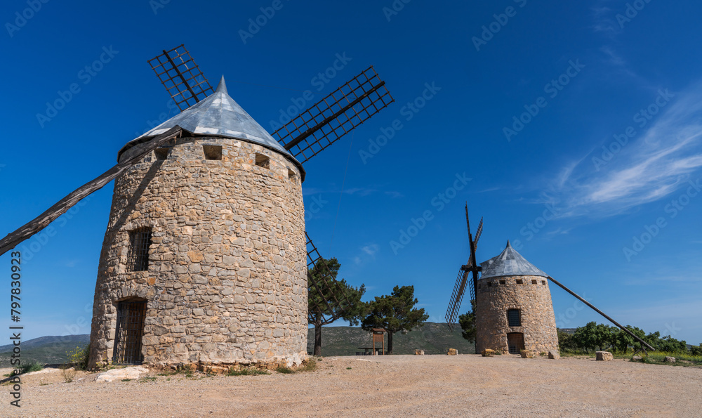 Typical old Spanish windmills on the hill surrounded by a green landscape, Spain.