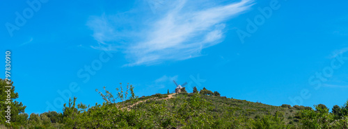 Typical old Spanish windmills on the hill surrounded by a green landscape, Spain.