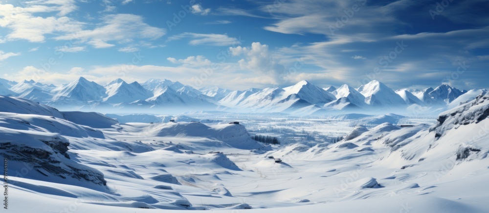 Snowy mountains under blue sky with clouds. Panoramic view.