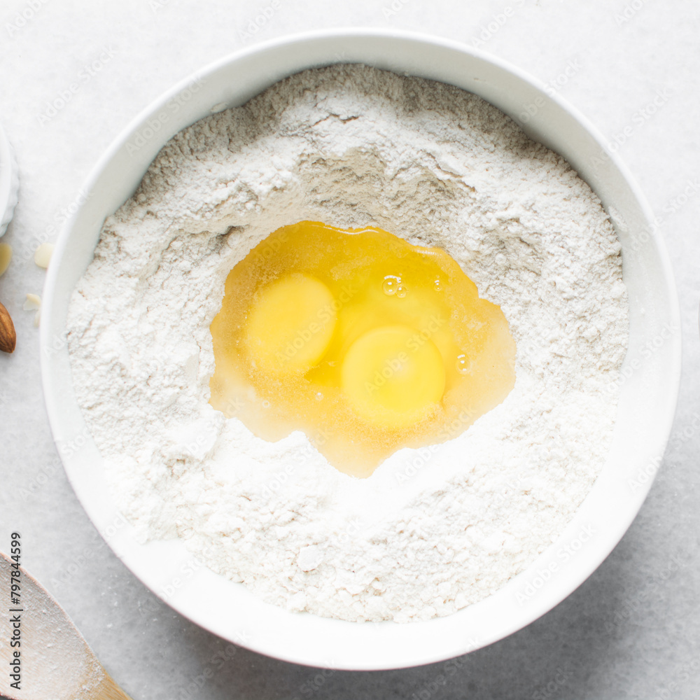 making almond biscotti dough in a white bowl, process of making almond cantucci cookie dough in ceramic mixing bowl, flatlay of biscotti cookie dough or twice baked cookies making almond biscotti dough in a white bowl, process of making almond cantucci cookie dough in ceramic mixing bowl, flatlay of biscotti cookie dough or twice baked cookies