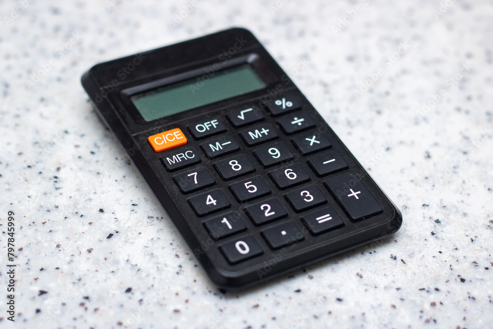 Black calculator on white counter, office equipment, communication device Black calculator on white counter, office equipment, communication device