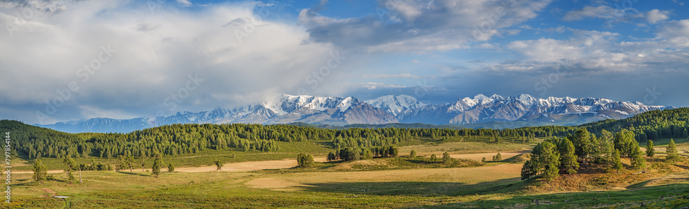 Fototapeta premium Panoramic view of mountain valley and snowy ridge, blue sky with clouds