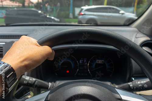 Hand of man holding steering wheel of car with one hand