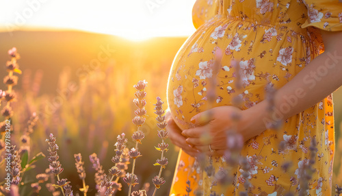 expectant mother in patterned yellow dress holding belly during golden hour in field