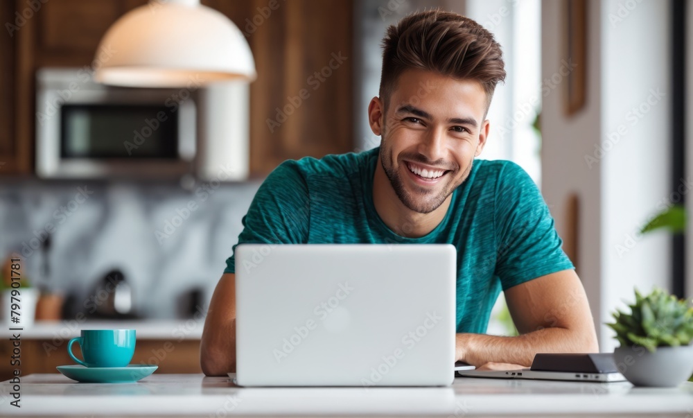 Potrait of an awesome Young man using the laptop and smiling at home. A man sitting by a table working on a laptop computer Potrait of an awesome Young man using the laptop and smiling at home. A man sitting by a table working on a laptop computer