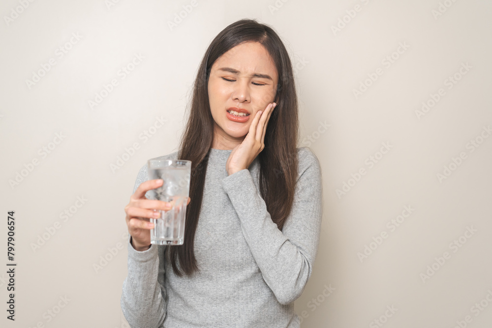 Suffering from toothache, hurt asian young woman touch cheek, face expression ache or feel pain, sensitive molar teeth, hand holding glass of water with ice, inflammation when drink cold, healthcare. Suffering from toothache, hurt asian young woman touch cheek, face expression ache or feel pain, sensitive molar teeth, hand holding glass of water with ice, inflammation when drink cold, healthcare.