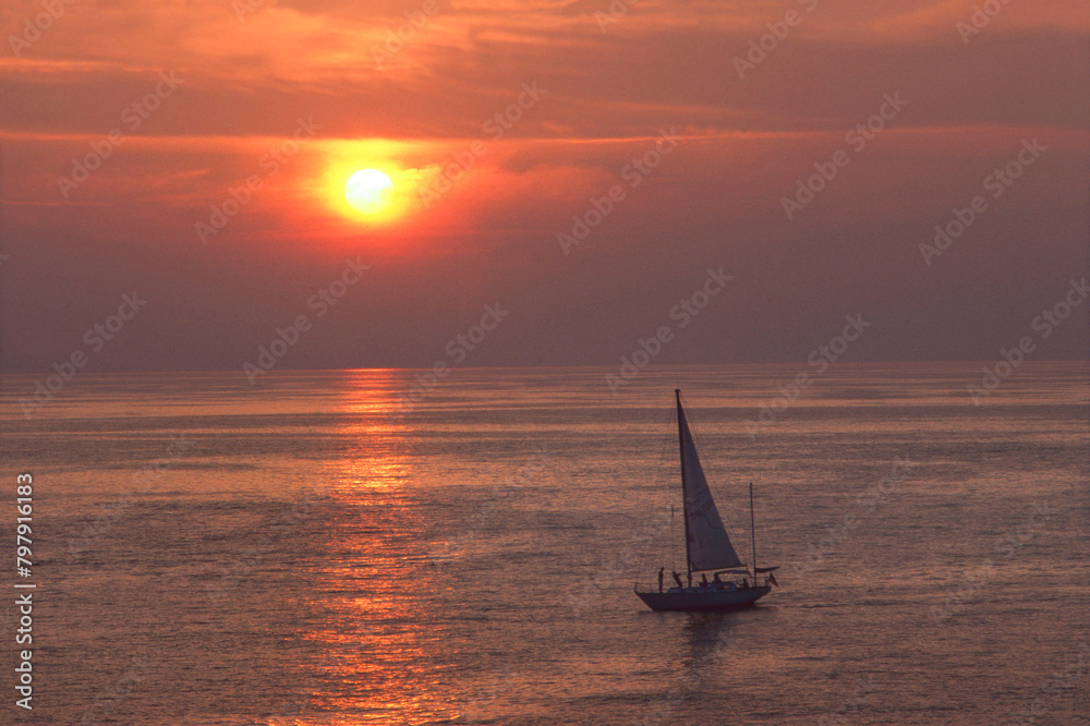 Fototapeta premium People sailing at sunset