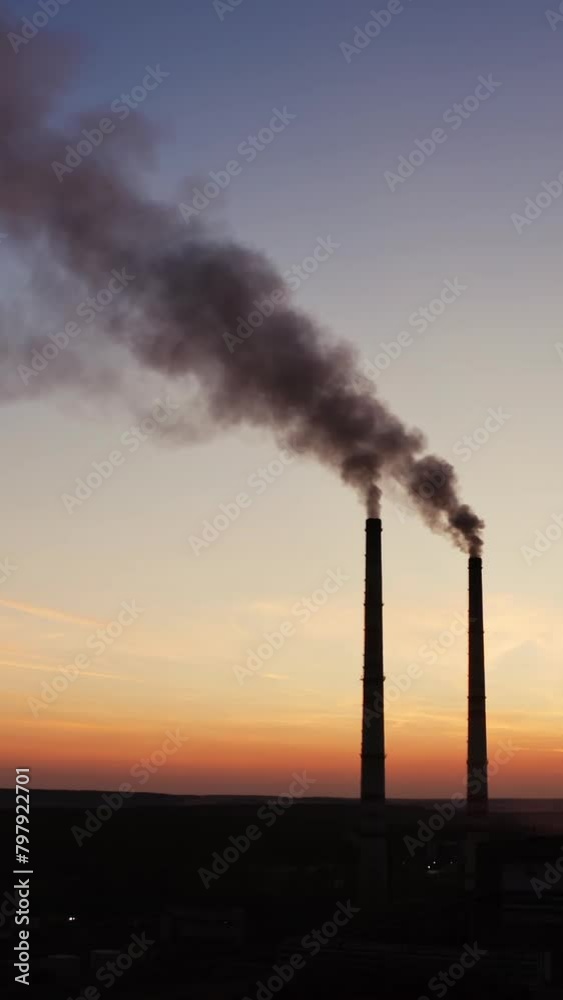 Dirty smoke from industrial pipes over the clear evening sky. Chemical smoke comes out of the pipes of power plant at darkness. Vertical video Dirty smoke from industrial pipes over the clear evening sky. Chemical smoke comes out of the pipes of power plant at darkness. Vertical video