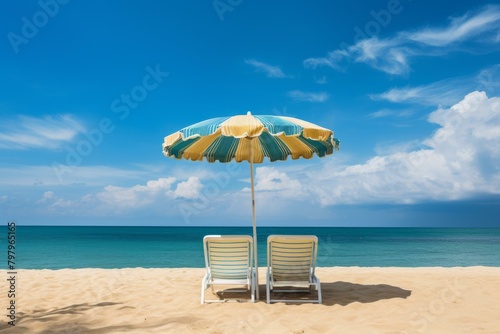 b Two empty beach chairs under a beach umbrella on a sandy beach with the ocean in the background 