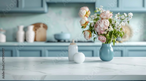 Selective focus on empty marble countertop in scandinavian style kitchen with blue furniture. cupboard with tablewear, fresh flowers in vases. minimalistic bright interior in apartment photo