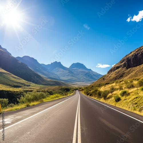 b'Road through mountain valley with blue sky and sun' © Adobe Contributor