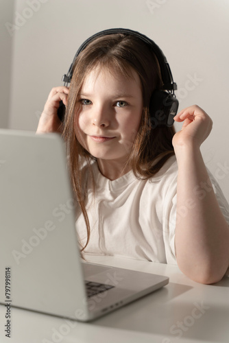 Little girl with laptop in headphones. Selected focus.