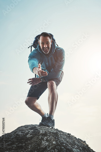 Climbing, helping and hand with man and fitness with backpack and mountain workout. Outdoor, nature and above with journey and adventure with a smile and portrait in on vacation with exercise