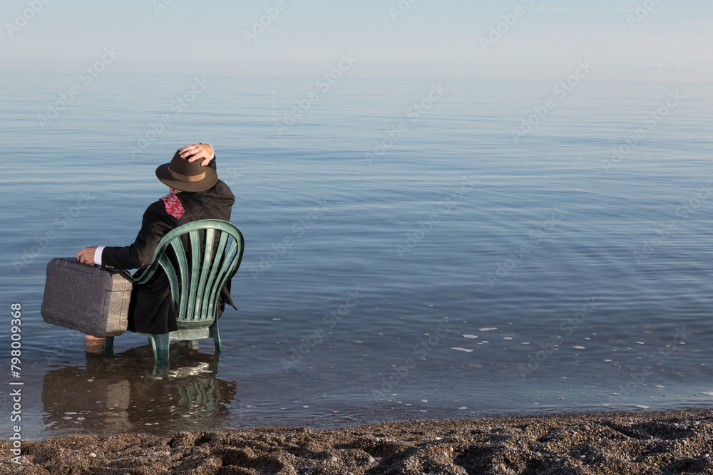 an unidentified  business man in a black suit sitting on a chair in the ocean