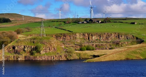 Aerial video of Naden Valley in Rochdale, Greater Manchester showing live stock grazing on a hill and wind turbines.  photo