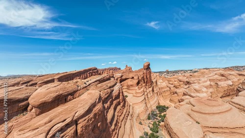 Flying over a canyon of red sandstone rock formations in Moab, UT on a sunny day with blue sky