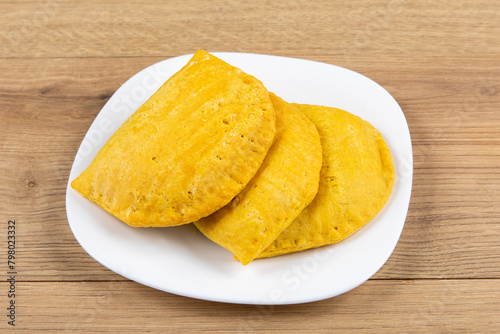 three spicy yellow Jamaican patties on a white plate
