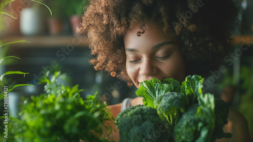 Smiling young woman smelling broccoli in kitchen at home.