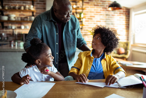 Father helping children with homework at kitchen table
