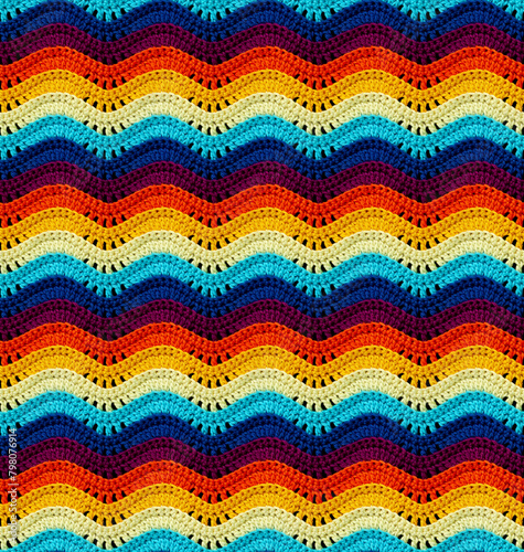 Seamless knitted pattern in the form of openwork waves is crocheted with threads of bright colors. Cotton yarn. Volumetric style.