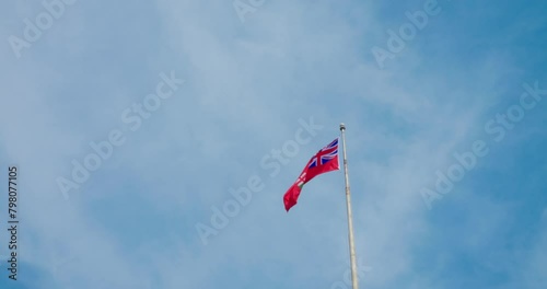 Unofficial Canadian flag waves against blue sky, symbol of cultural identity, civic pride in Canada. Visible wind, national colors in motion, represents Canada's unofficial emblem. photo