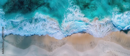Ocean waves roll onto sandy beach, captured in panoramic aerial view with space for text