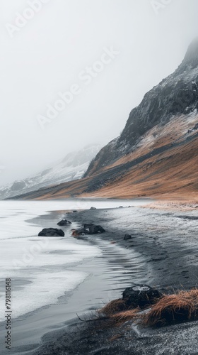 b'Black sand beach in Iceland with large rock formations in foreground and mountains in background' photo