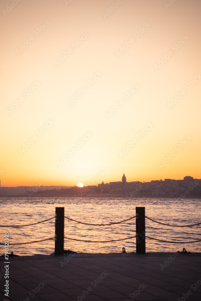 Obraz premium outstanding photography of a sunset in istanbul with the silhouette of the city skyline and the sun getting in near Galata tower, with birds flying around. copy space.