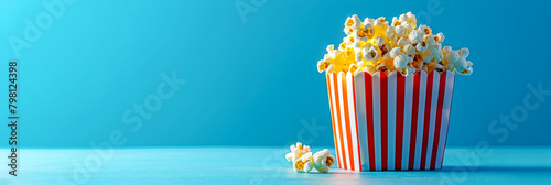 Delicious Popcorn in Striped Container on Blue Background
