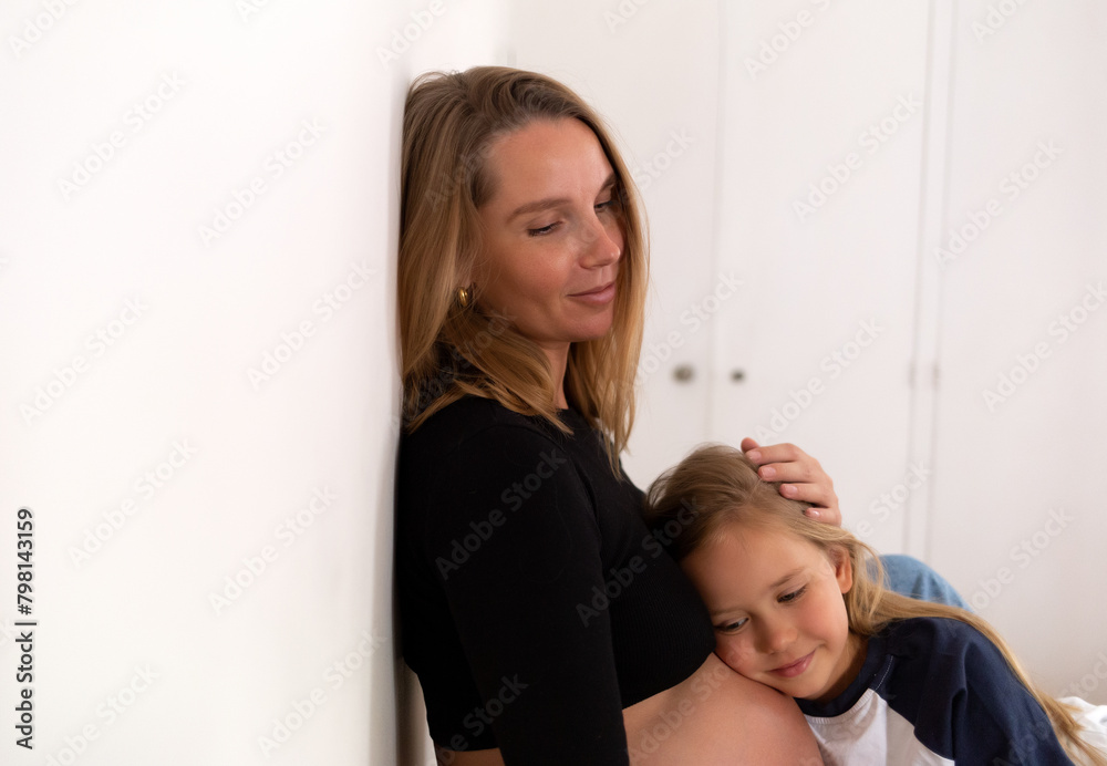 Little cute daughter hugging pregnant mother at home Little cute daughter hugging pregnant mother at home