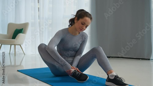 Caucasian sad woman displeased unwell girl suffer leg pain sport trauma upset sportswoman fitness lady athlete female massaging foot at home workout training painful muscle ache callus injury damage photo