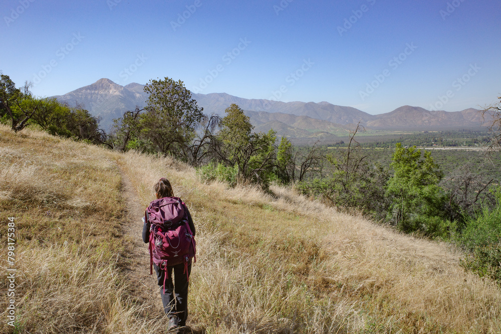 Obraz premium Santiago, Chile - 25 Nov, 2023: A Female hiker on a trail in the Andes Mountains near Pirque, Chile