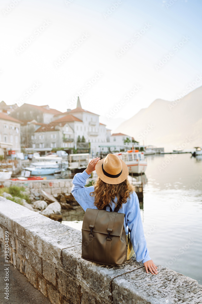 Happy young woman standing on bridge enjoys the view of the city. Back view. Europe travel. Lifestyle, vacation, tourism, nature, active life.