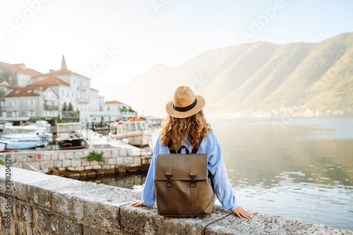 Happy young woman standing on bridge enjoys the view of the city. Back view. Europe travel. Lifestyle, vacation, tourism, nature, active life.