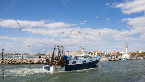 chalutier en mer Méditerranée revenant de la pêche avec des mouettes le suivant devant le port de Port Camargue en France