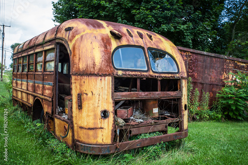 Abandoned rusty yellow school bus in overgrown outdoor setting  © littleny