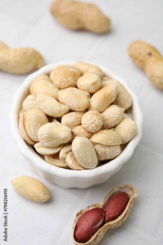 Fresh peeled peanuts in bowl on white tiled table, closeup Fresh peeled peanuts in bowl on white tiled table, closeup