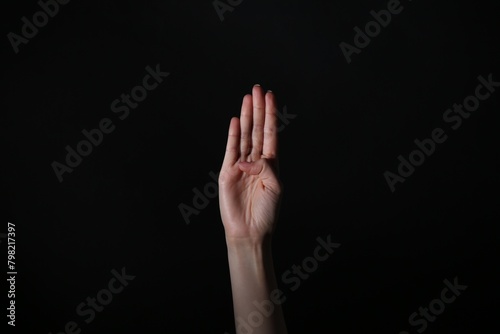 Woman showing open palm on black background, closeup