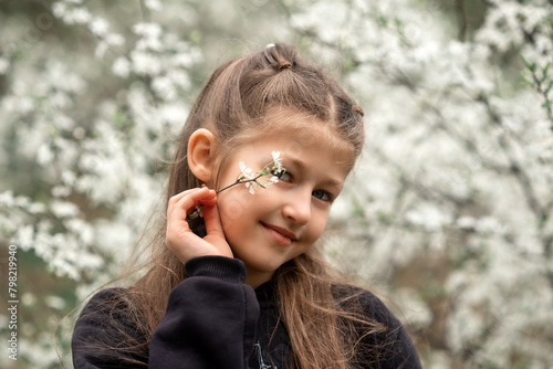 portrait of a little girl in a blooming garden with a flower in her hand
