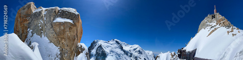 Haute-Savoie, France, 04-25-2024: blue sky and panoramic view of L’Aiguille du Midi (Needle at midday), the highest spire (3.842 m) of the Aiguilles de Chamonix, with the Mont Blanc massif peaks  photo