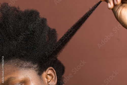 woman stretching her curly hair to emphasize shrinkage, 4c hair stretched to show shrinkage