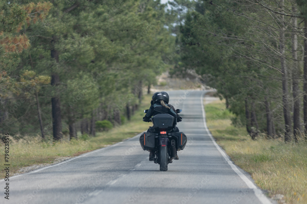 A man and woman are riding a motorcycle down a country road A man and woman are riding a motorcycle down a country road