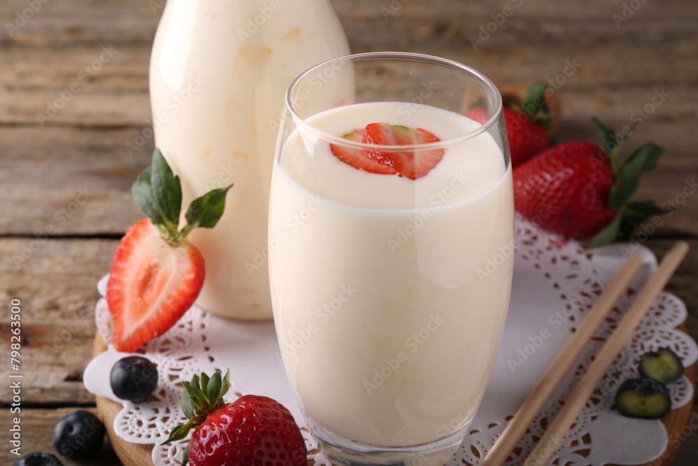 Tasty yogurt in glass, straws and berries on wooden table, closeup Tasty yogurt in glass, straws and berries on wooden table, closeup