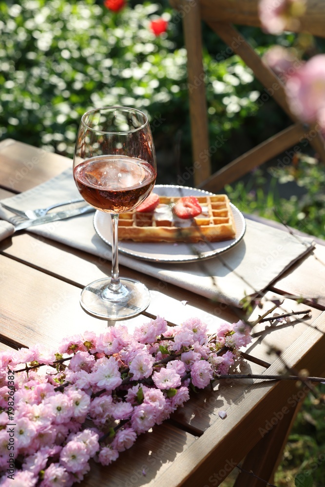 Delicious Belgian waffle with fresh strawberries and wine served on table in spring garden Delicious Belgian waffle with fresh strawberries and wine served on table in spring garden