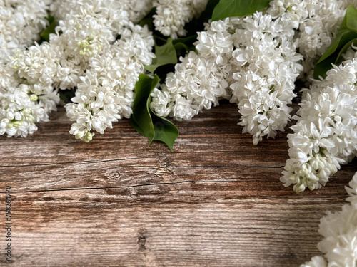 Twigs of white lilac on a wooden background with a copy of the text space, top view. A horizontal banner with white flowers . 