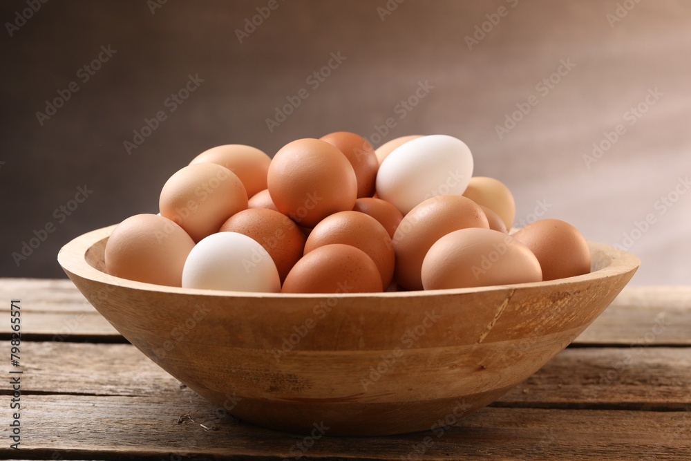 Chicken eggs in bowl on wooden table, closeup Chicken eggs in bowl on wooden table, closeup