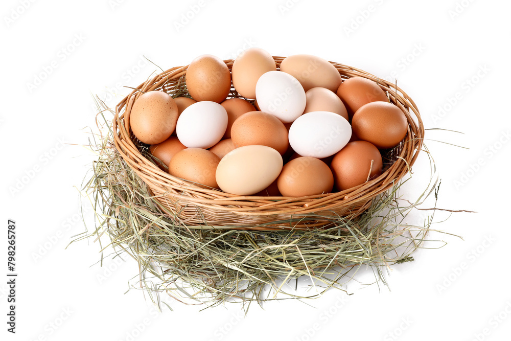 Fresh chicken eggs in wicker basket and dried hay isolated on white Fresh chicken eggs in wicker basket and dried hay isolated on white
