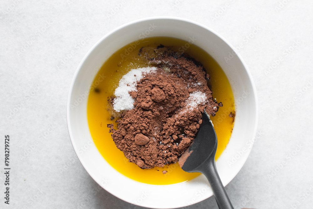 overhead view of melted butter white sugar and brown sugar cocoa powder in a white bowl, the process of making brownies, mixing butter and sugar to make brownies overhead view of melted butter white sugar and brown sugar cocoa powder in a white bowl, the process of making brownies, mixing butter and sugar to make brownies