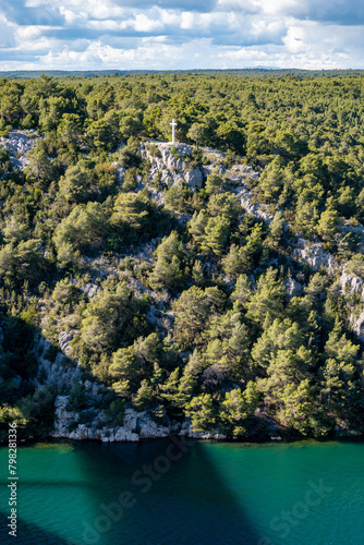 White, stone cross memorial, built on th eedge of steep cliff above Krka river, Croatia, near the town of Skradin, Croatia. photo
