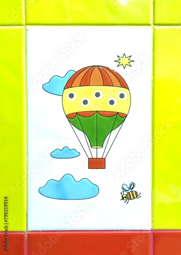 Creative arts painting of a hot air balloon, bee, clouds on a tile wall